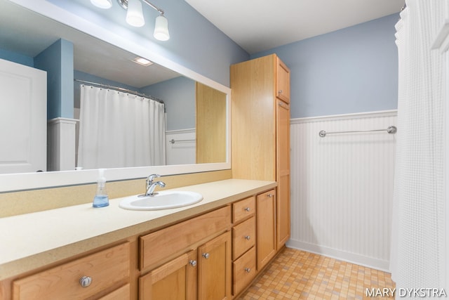 full bath featuring vanity and a wainscoted wall