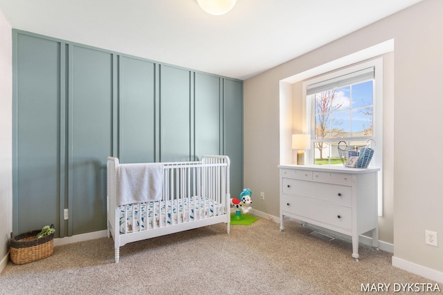 bedroom with carpet floors, baseboards, and a nursery area