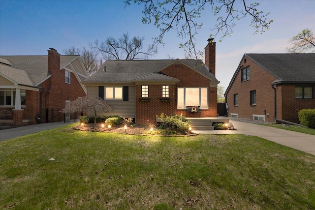 bungalow with brick siding, a front yard, a gate, a chimney, and concrete driveway