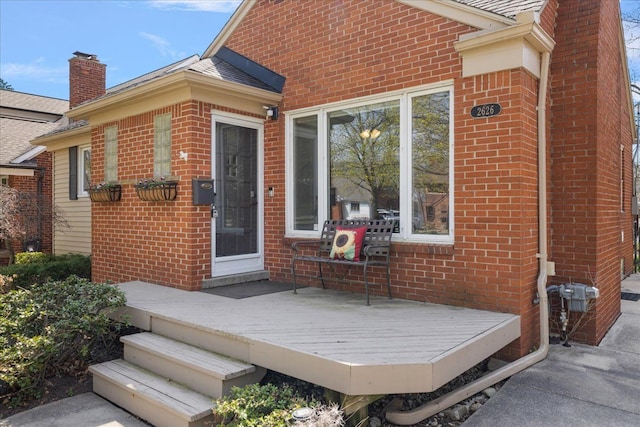 property entrance with brick siding and a wooden deck