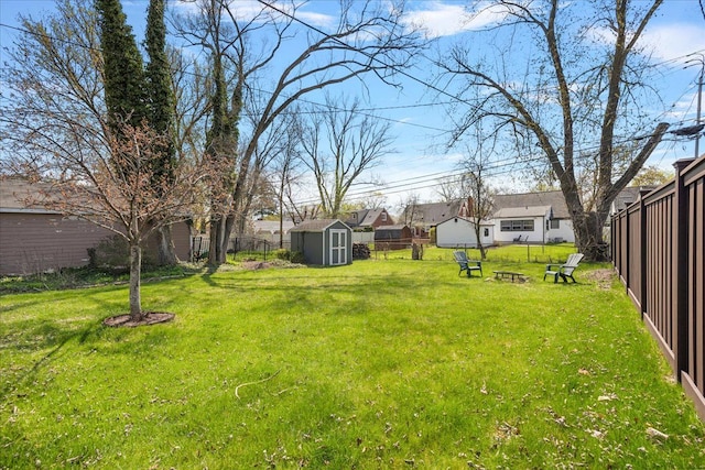 view of yard with an outdoor structure, fence, a storage shed, and a residential view