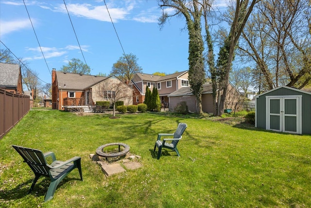 view of yard featuring a residential view, fence, an outdoor structure, a shed, and an outdoor fire pit