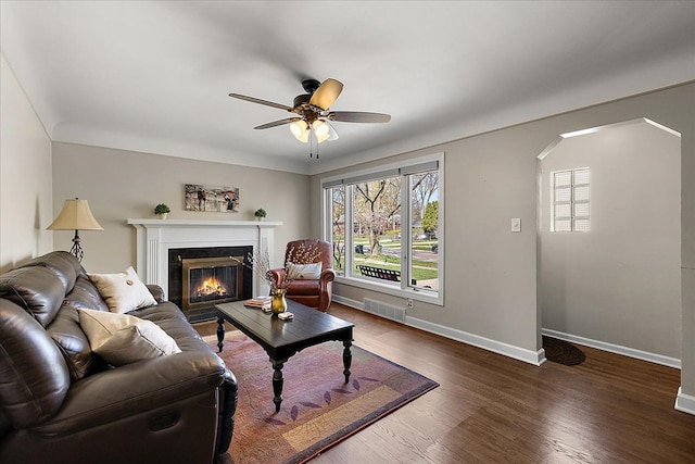 living room with a glass covered fireplace, baseboards, plenty of natural light, and ceiling fan