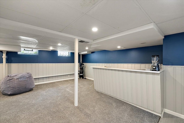 below grade area with carpet floors, recessed lighting, visible vents, and a wainscoted wall