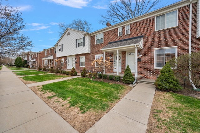 view of property featuring a residential view, a front lawn, and brick siding