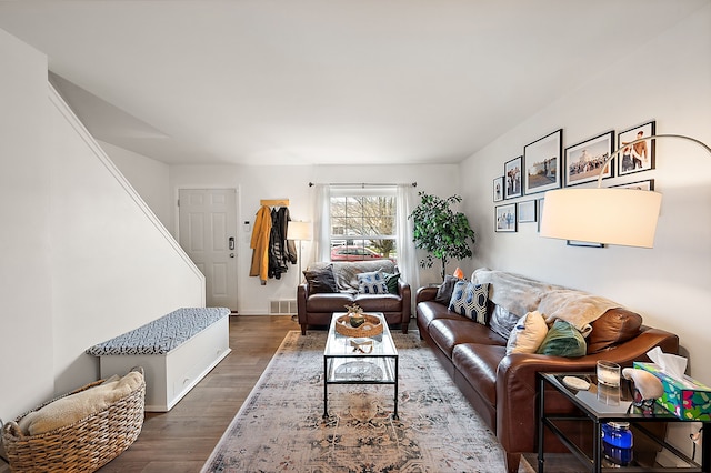 living area featuring stairway, baseboards, wood finished floors, and visible vents