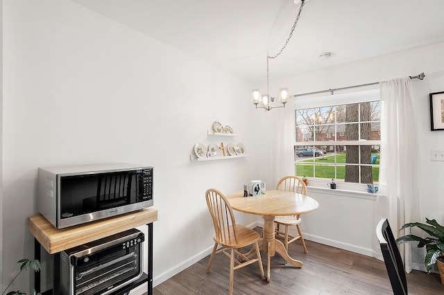dining room with baseboards, wood finished floors, and a notable chandelier