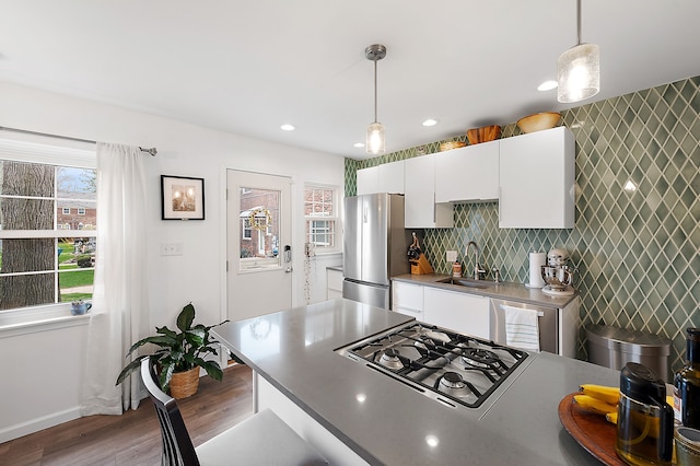 kitchen featuring a sink, freestanding refrigerator, stovetop, and white cabinetry