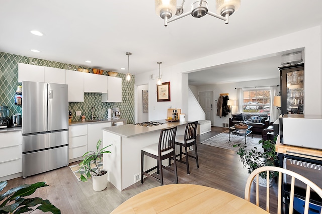 kitchen with appliances with stainless steel finishes, a breakfast bar area, light wood-type flooring, and white cabinetry
