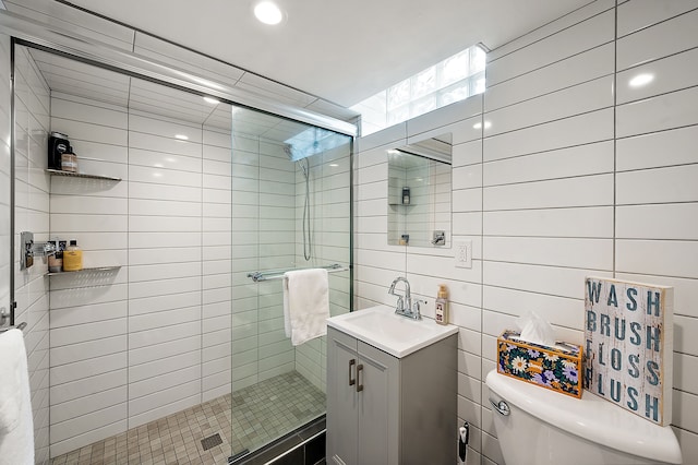 bathroom with vanity, toilet, tile walls, and a stall shower