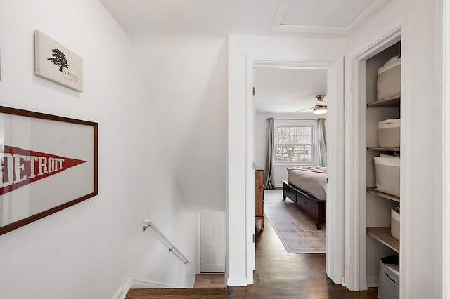 corridor with baseboards, attic access, dark wood-style floors, and an upstairs landing
