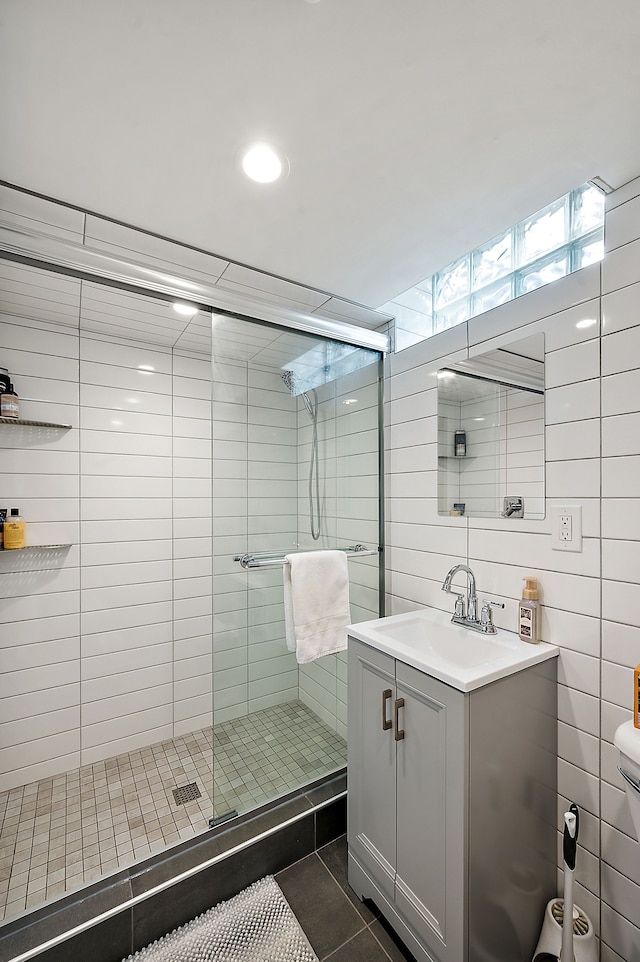 bathroom featuring vanity, tile patterned floors, a shower stall, and tile walls