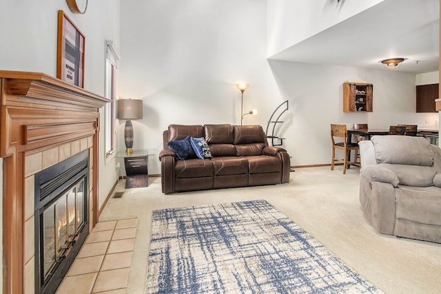 living room with baseboards, light colored carpet, a high ceiling, and a tile fireplace