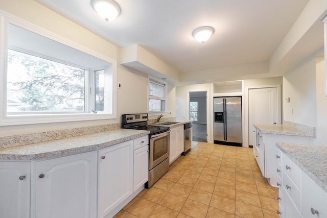 kitchen featuring white cabinets, a sink, light countertops, stainless steel appliances, and light tile patterned floors