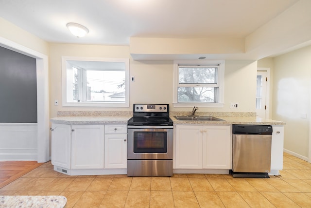 kitchen featuring plenty of natural light, a sink, white cabinets, and stainless steel appliances