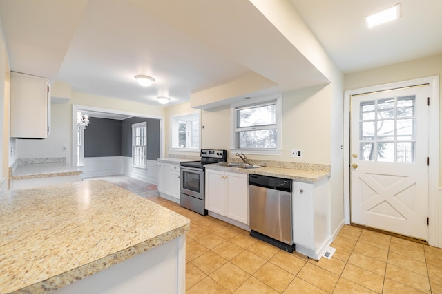 kitchen featuring light countertops, white cabinets, a sink, light tile patterned floors, and stainless steel appliances
