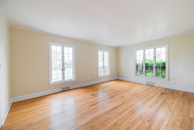 unfurnished room featuring crown molding, baseboards, light wood-style floors, and visible vents
