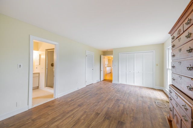 unfurnished bedroom with baseboards, wood finished floors, and ensuite bath