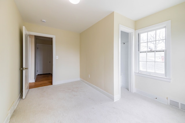 unfurnished bedroom with baseboards, light carpet, and visible vents