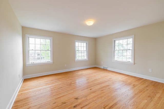 empty room featuring a healthy amount of sunlight, light wood-style floors, and visible vents