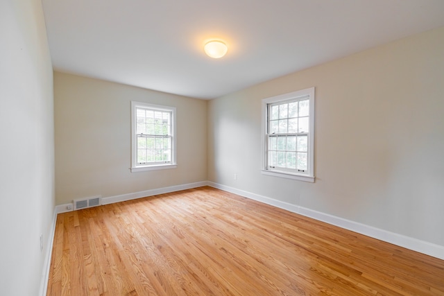 unfurnished room featuring a healthy amount of sunlight, baseboards, light wood finished floors, and visible vents