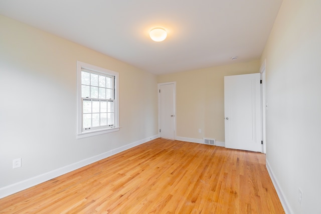 spare room with baseboards, light wood-style flooring, and visible vents