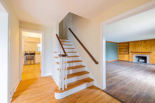 stairway featuring baseboards, wood finished floors, and a fireplace