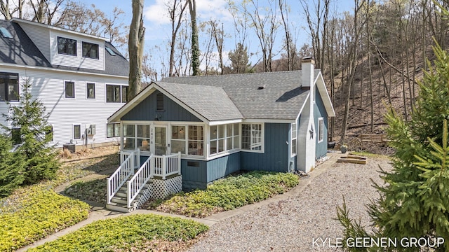 rear view of house with roof with shingles, a chimney, and a sunroom