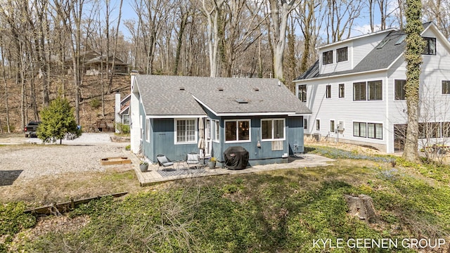 rear view of property with roof with shingles and a patio area