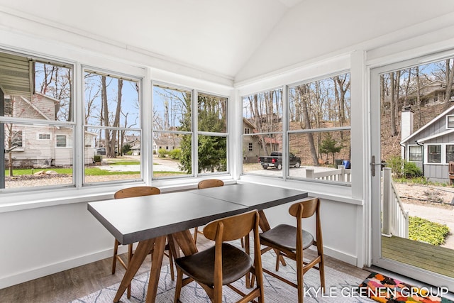 sunroom featuring baseboards, a healthy amount of sunlight, and vaulted ceiling