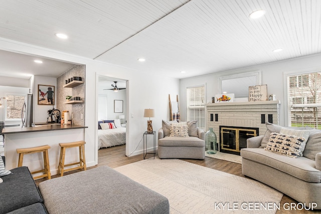 living room with ceiling fan, a brick fireplace, recessed lighting, wood finished floors, and wood ceiling