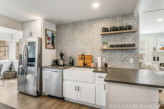 kitchen featuring dark countertops, appliances with stainless steel finishes, a sink, and tasteful backsplash