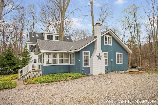 exterior space featuring roof with shingles, a chimney, and a sunroom