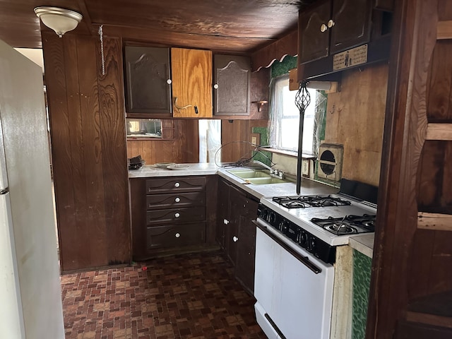 kitchen with a sink, light countertops, white appliances, and dark brown cabinets