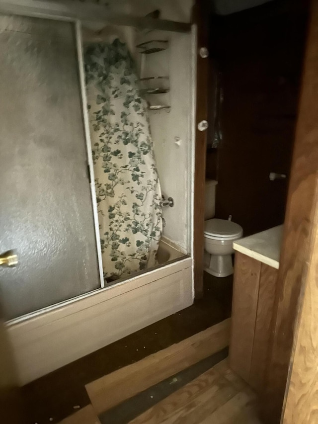 bathroom featuring toilet, wood finished floors, and shower / bath combo with shower curtain