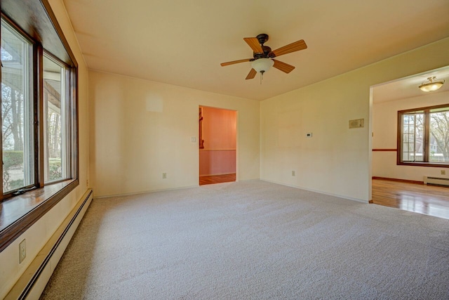 unfurnished room with carpet flooring, baseboard heating, a ceiling fan, baseboards, and a baseboard heating unit