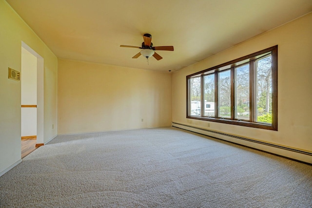 carpeted empty room featuring a ceiling fan and baseboard heating