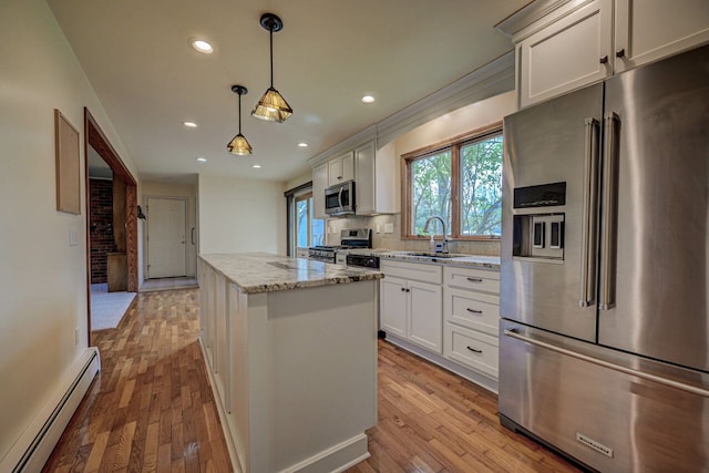 kitchen with appliances with stainless steel finishes, a sink, light wood-style flooring, a center island, and a baseboard heating unit