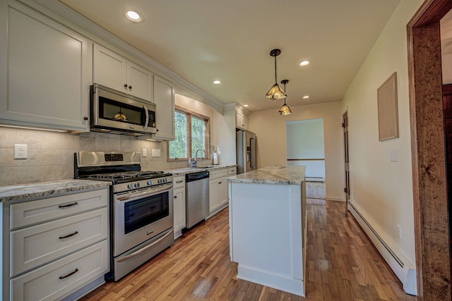kitchen with appliances with stainless steel finishes, baseboard heating, light wood-style flooring, a center island, and backsplash