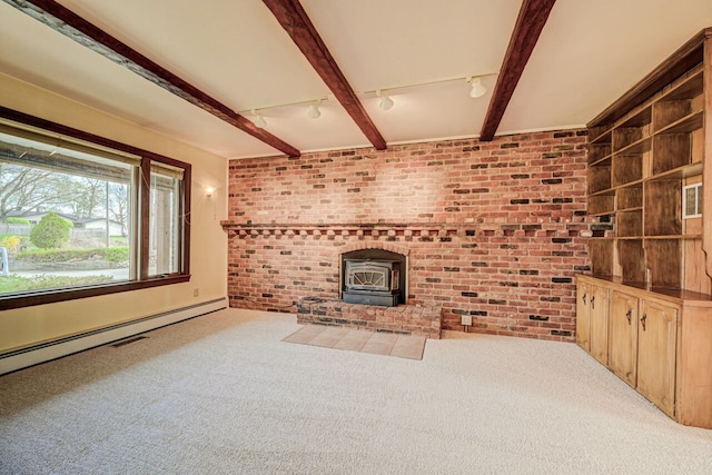 unfurnished living room with carpet flooring, brick wall, track lighting, and a wood stove