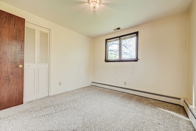 unfurnished bedroom with carpet floors, a baseboard radiator, a closet, and visible vents