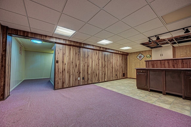 finished below grade area featuring wooden walls, baseboards, and a paneled ceiling