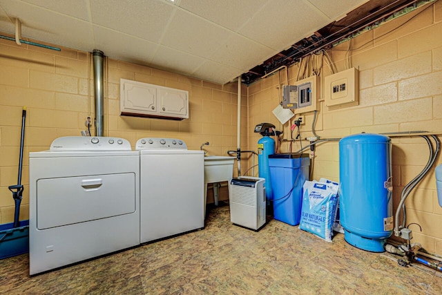 washroom featuring separate washer and dryer, cabinet space, and concrete block wall