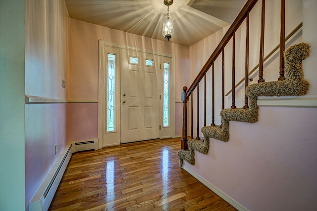 foyer with baseboards, a baseboard heating unit, stairs, and wood finished floors