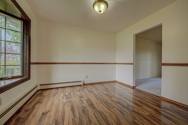spare room featuring baseboards, a baseboard radiator, and wood finished floors