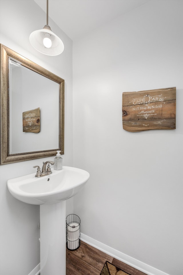 bathroom featuring baseboards, a sink, and wood finished floors