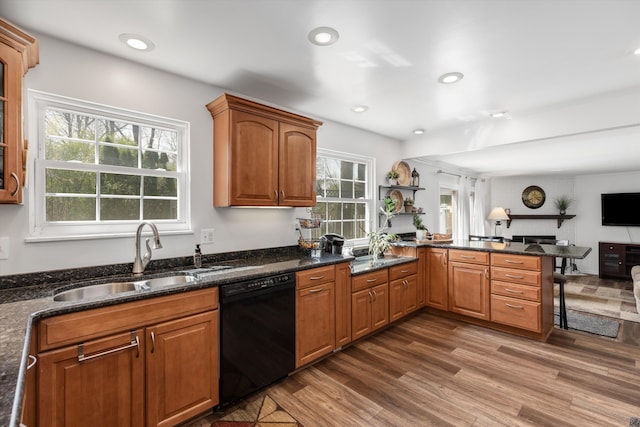 kitchen featuring a peninsula, wood finished floors, a breakfast bar, a sink, and dishwasher