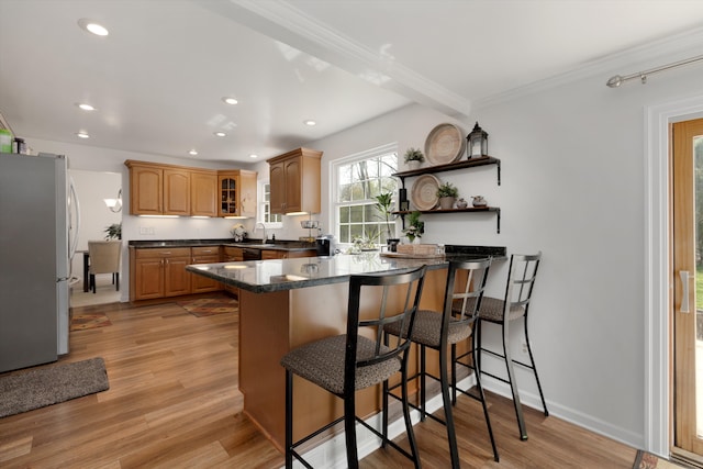 kitchen with crown molding, a breakfast bar area, freestanding refrigerator, a peninsula, and recessed lighting