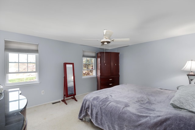 bedroom featuring light colored carpet, baseboards, ceiling fan, and visible vents