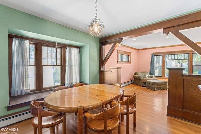 dining space with a healthy amount of sunlight, crown molding, baseboard heating, and light wood finished floors